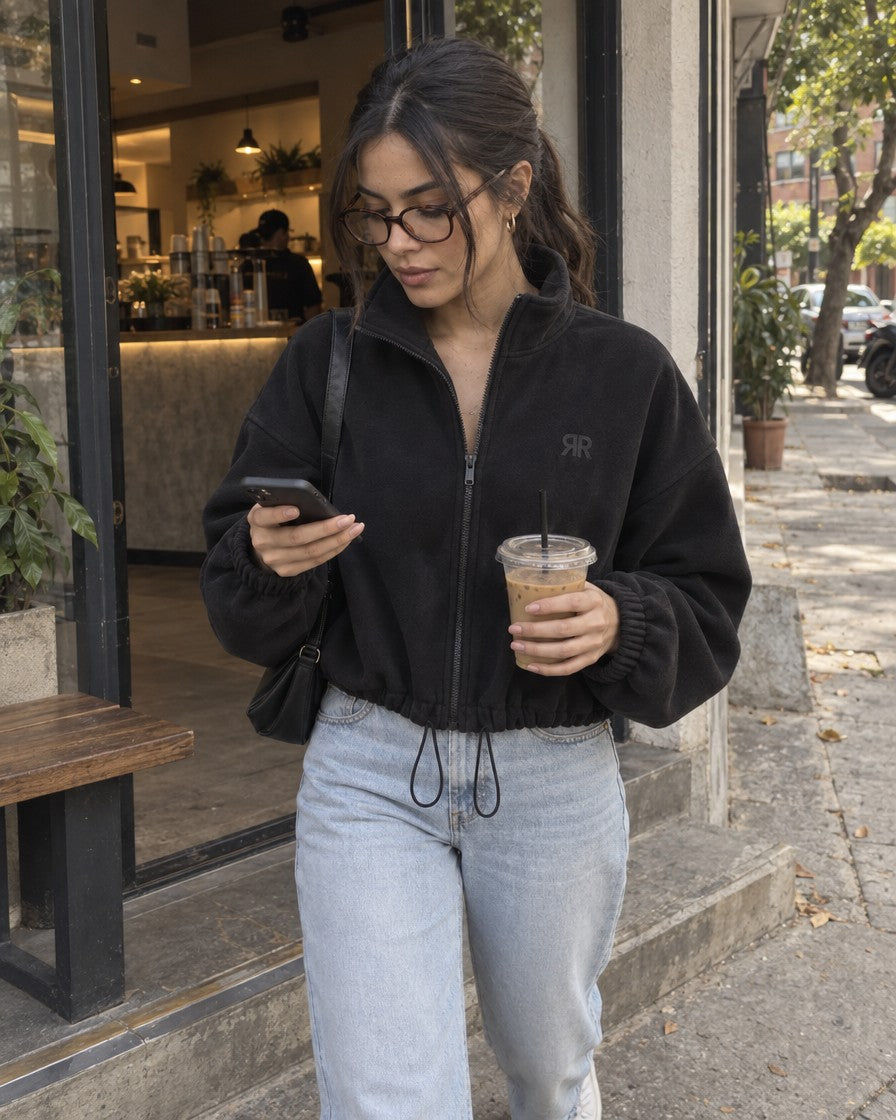 Mujer con la Chaqueta Era negra, jean y tenis en una terraza